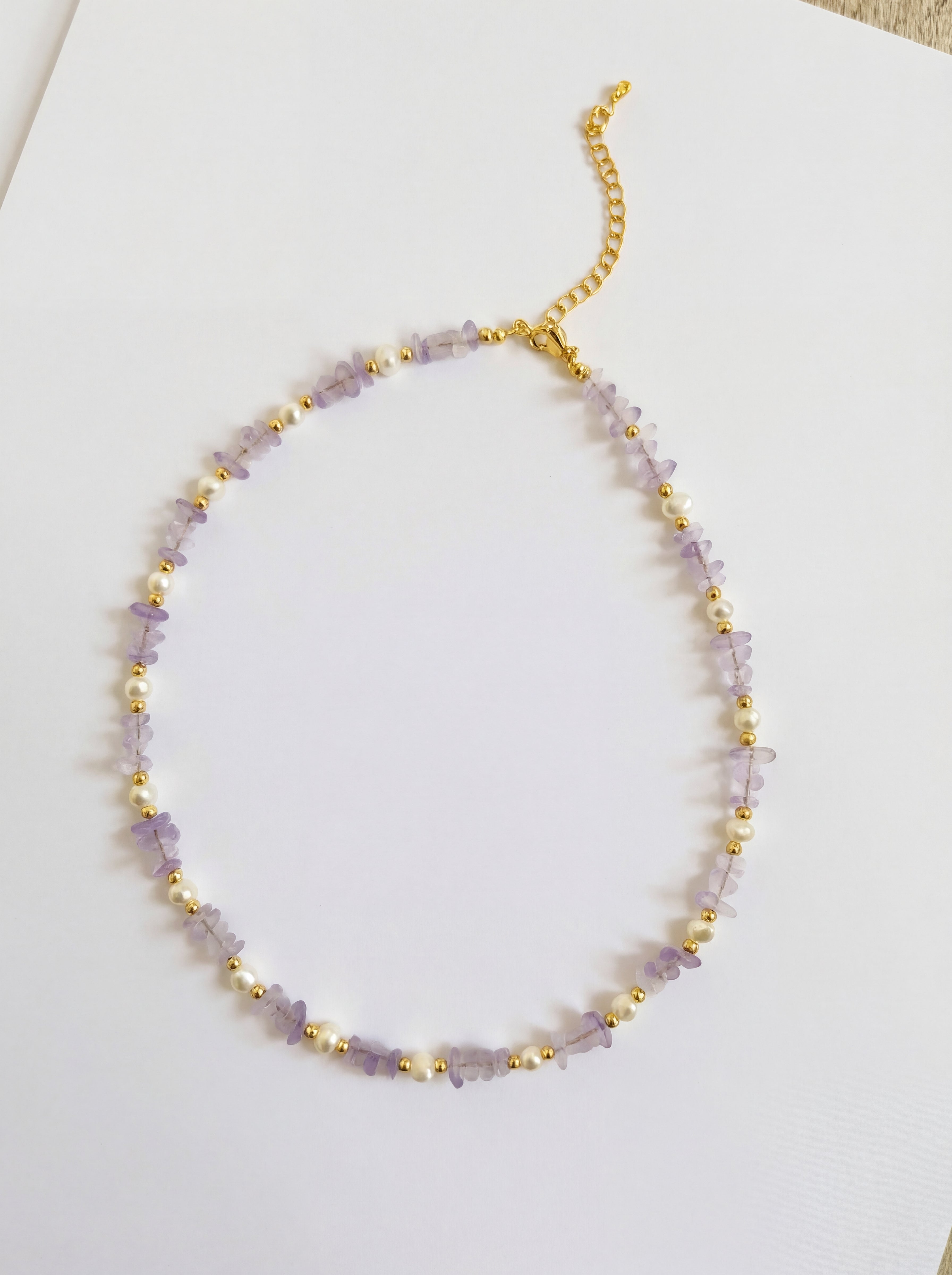 Necklace with purple beads and gold accents on a white background
