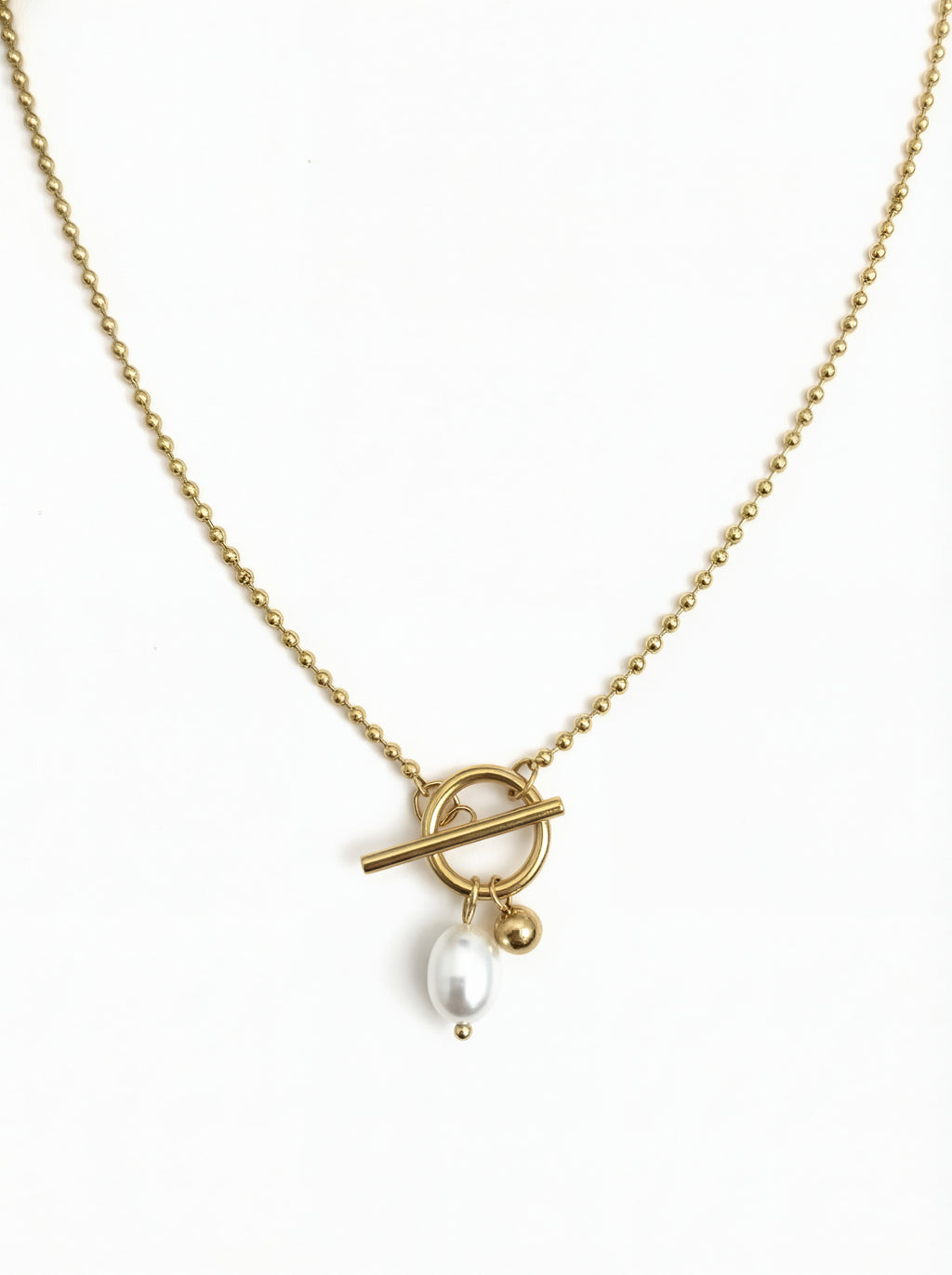 Gold necklace with a toggle clasp and pearl pendant on a white background