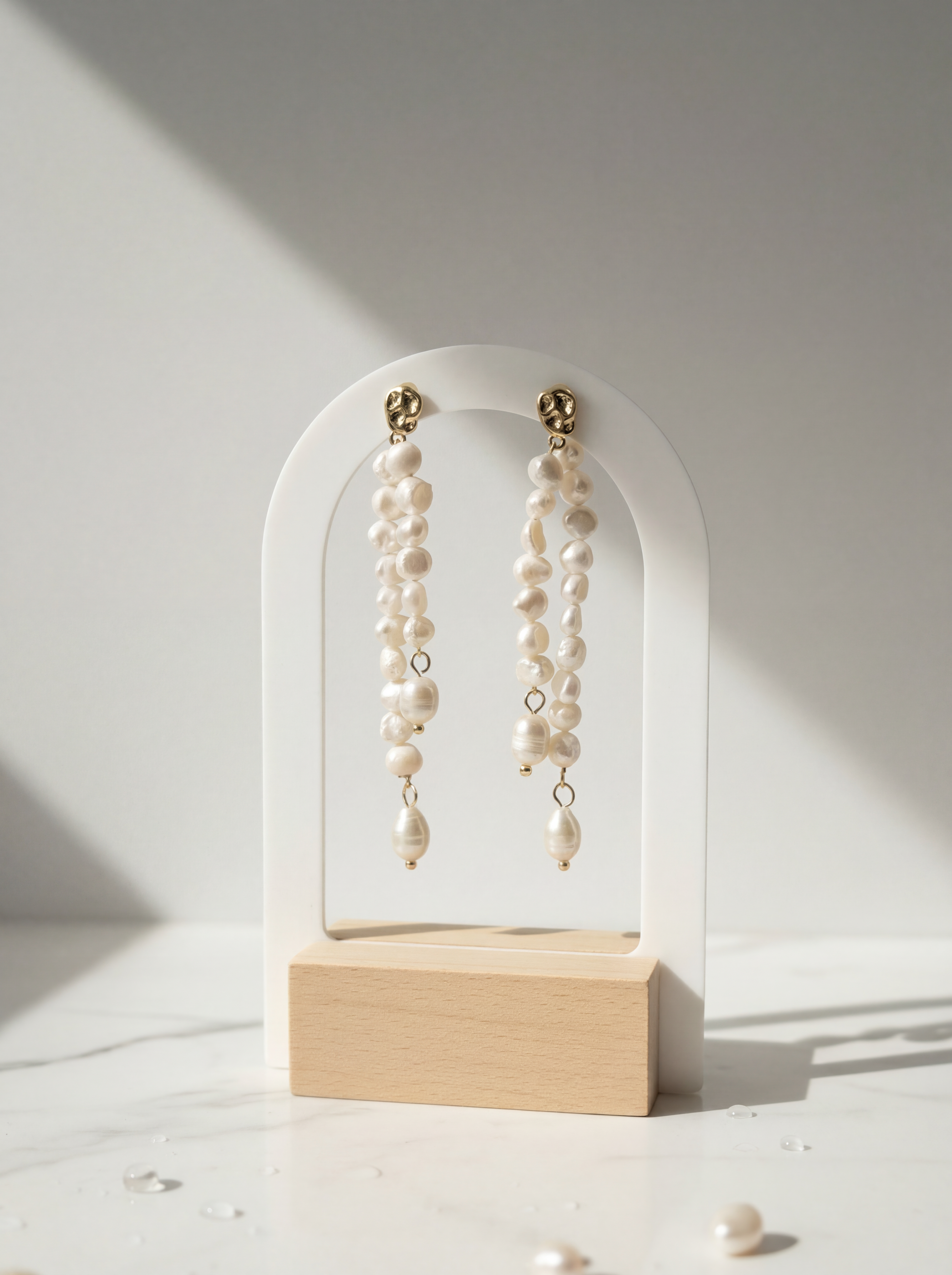 Pearl earrings on a white arch stand with a light background