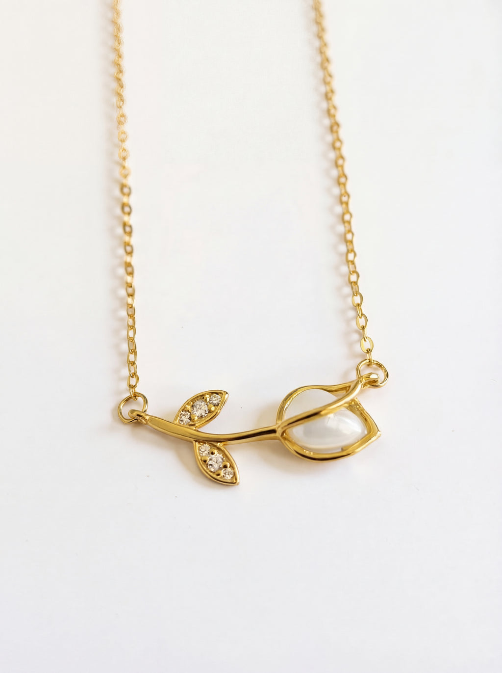 Gold necklace with leaf design on a white background