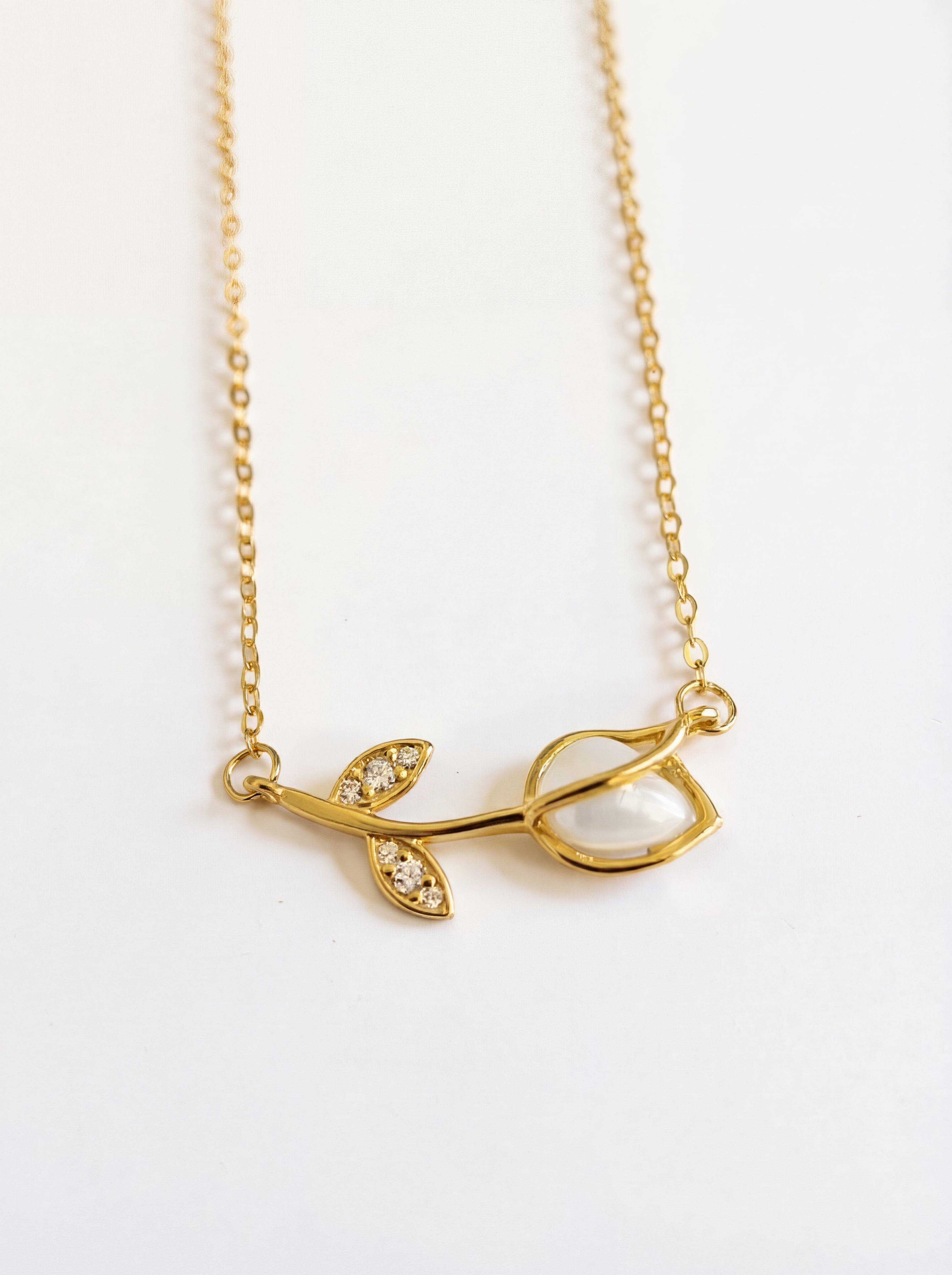 Gold necklace with leaf design on a white background