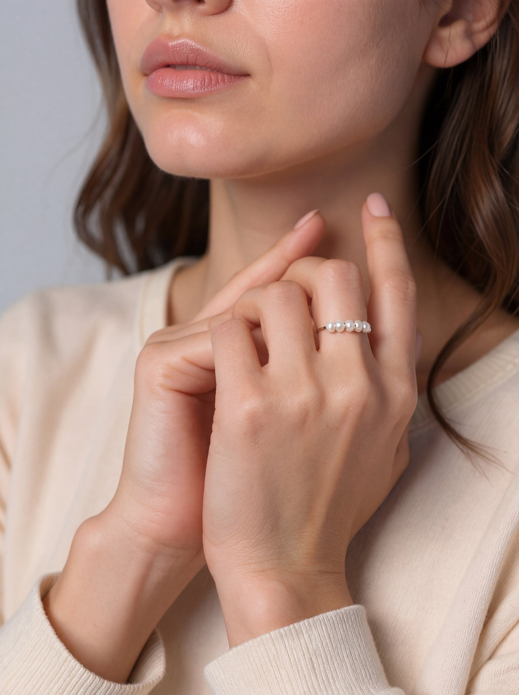 Close-up of a woman wearing a silver ring on her finger against a neutral background
