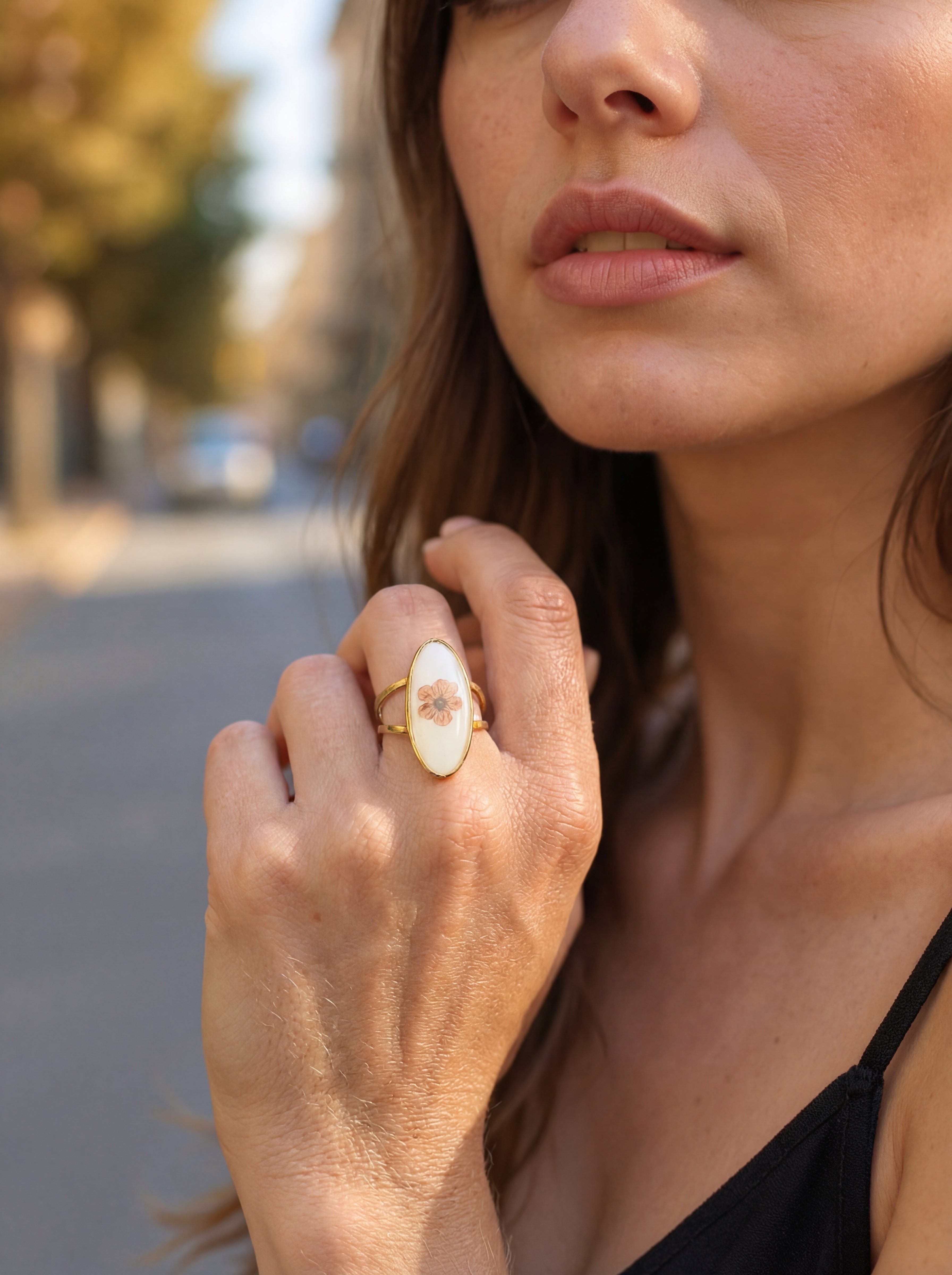 Close-up of a woman's hand wearing a decorative ring outdoors.