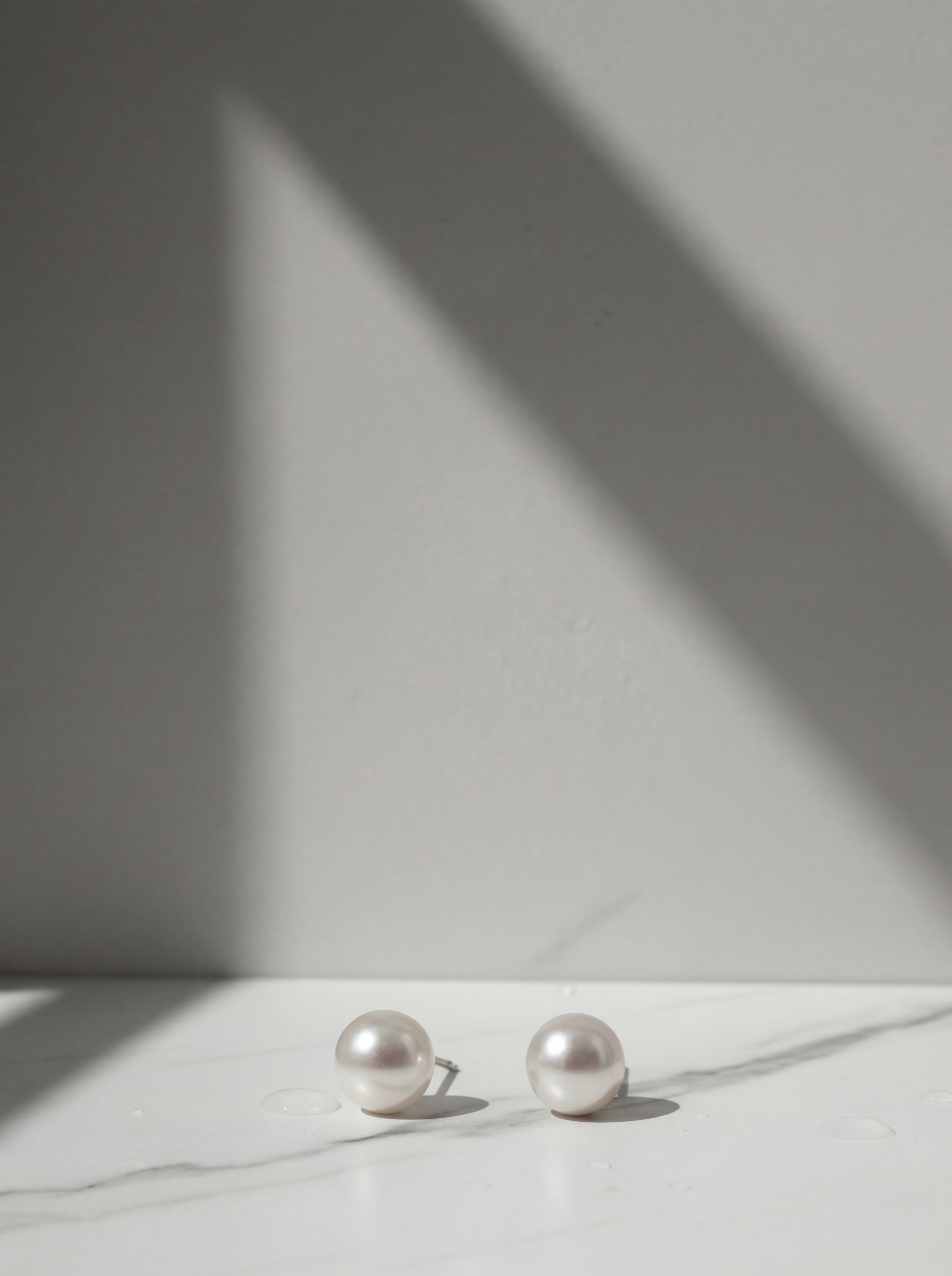 Pearl earrings on a white surface with a soft shadow on a light gray background