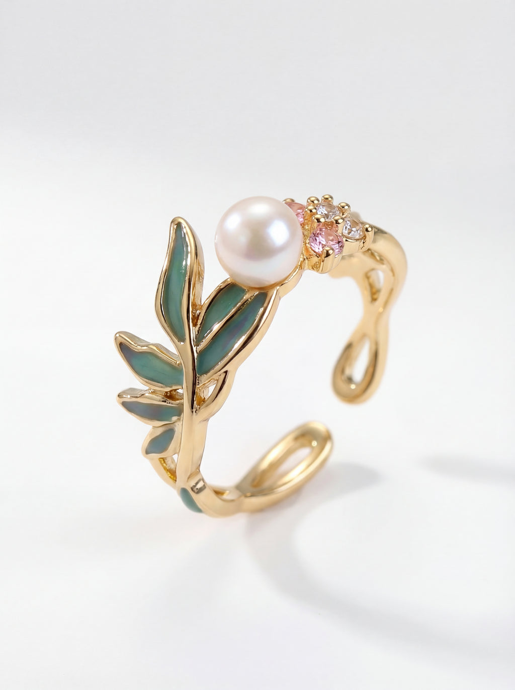 Gold ring with pearl and gemstone on a light gray background