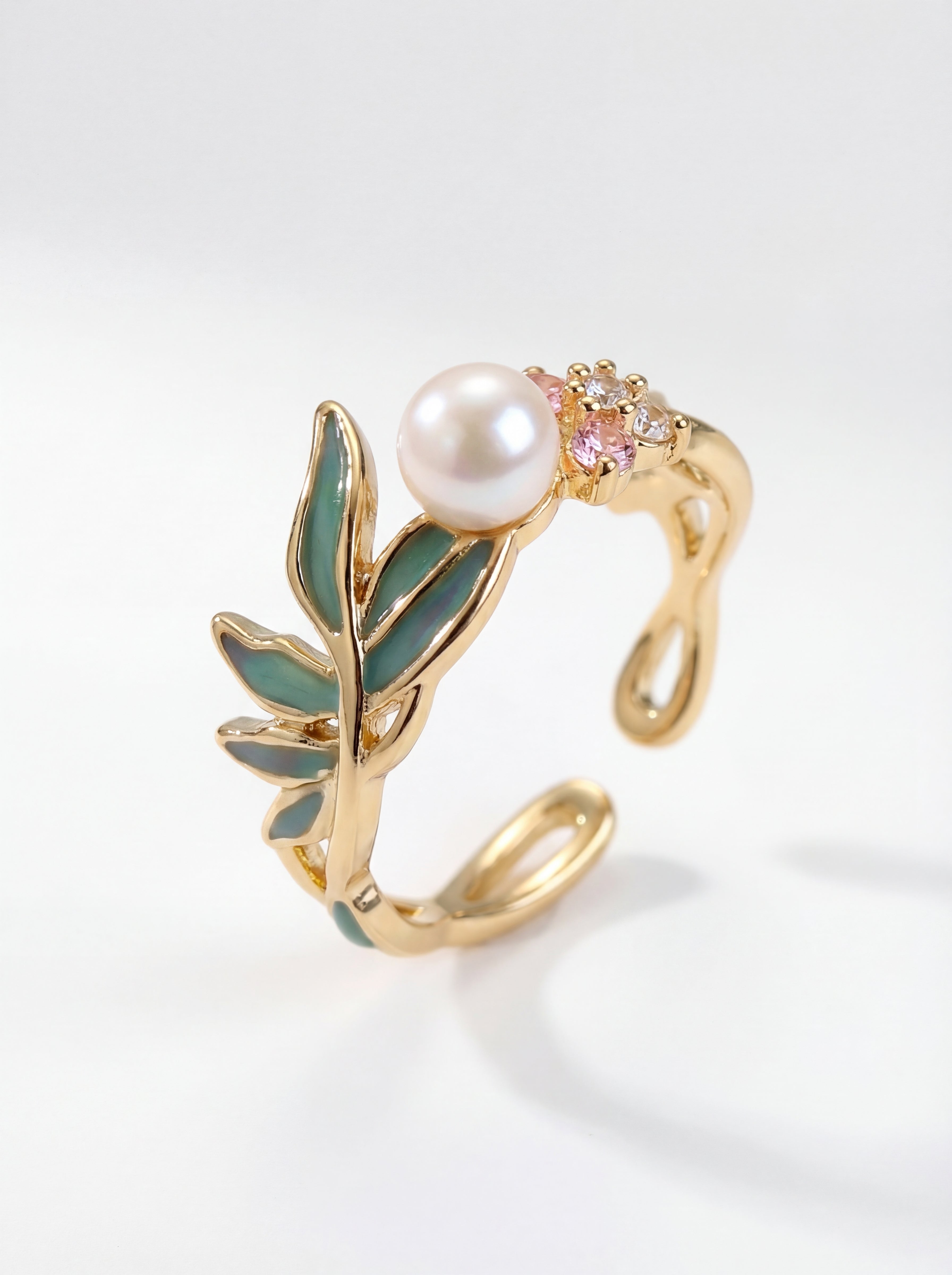 Gold ring with pearl and gemstone on a light gray background