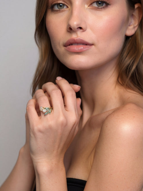 Woman wearing a ring with a green gemstone against a neutral background