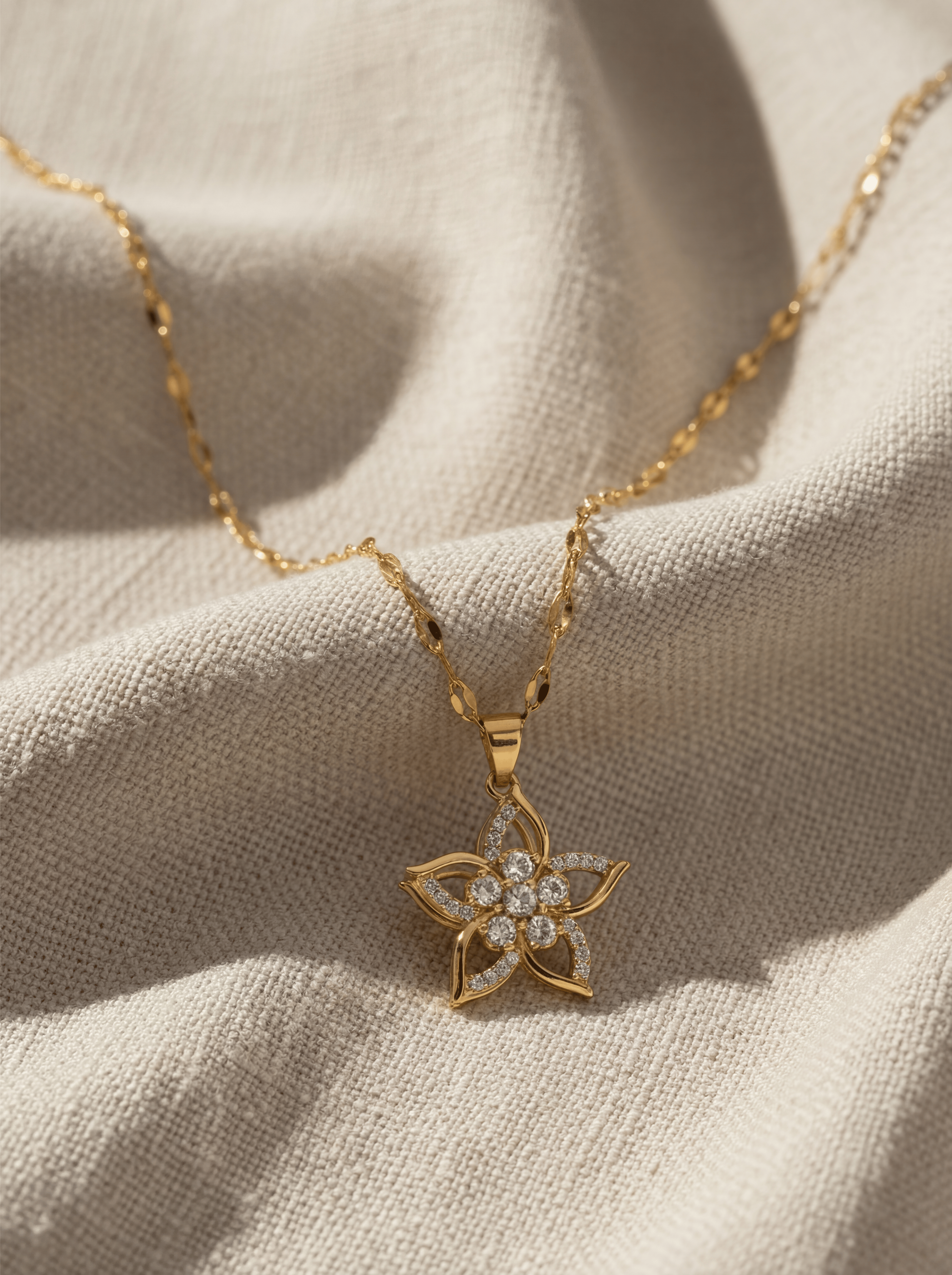 Gold necklace with a star-shaped pendant on a beige fabric background