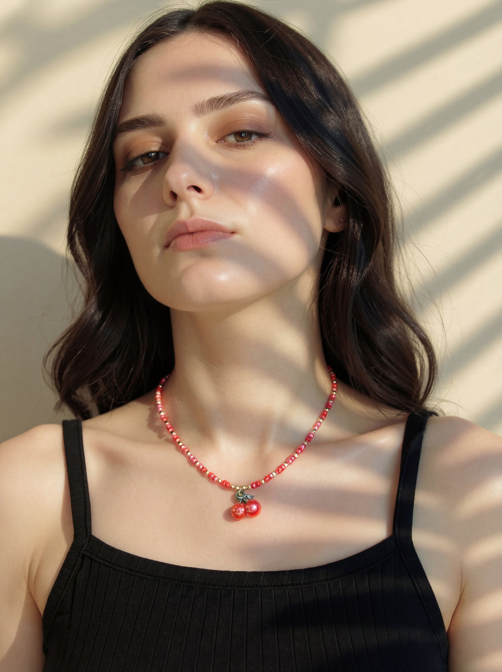 Woman wearing a red beaded necklace with a neutral background