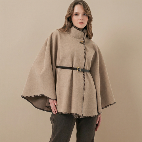 A beige oversized poncho featuring a dark blanket stitch trim and a belted waist.