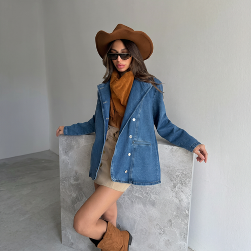 A woman wearing an oversized blue double breasted denim blazer with a brown cowboy hat.