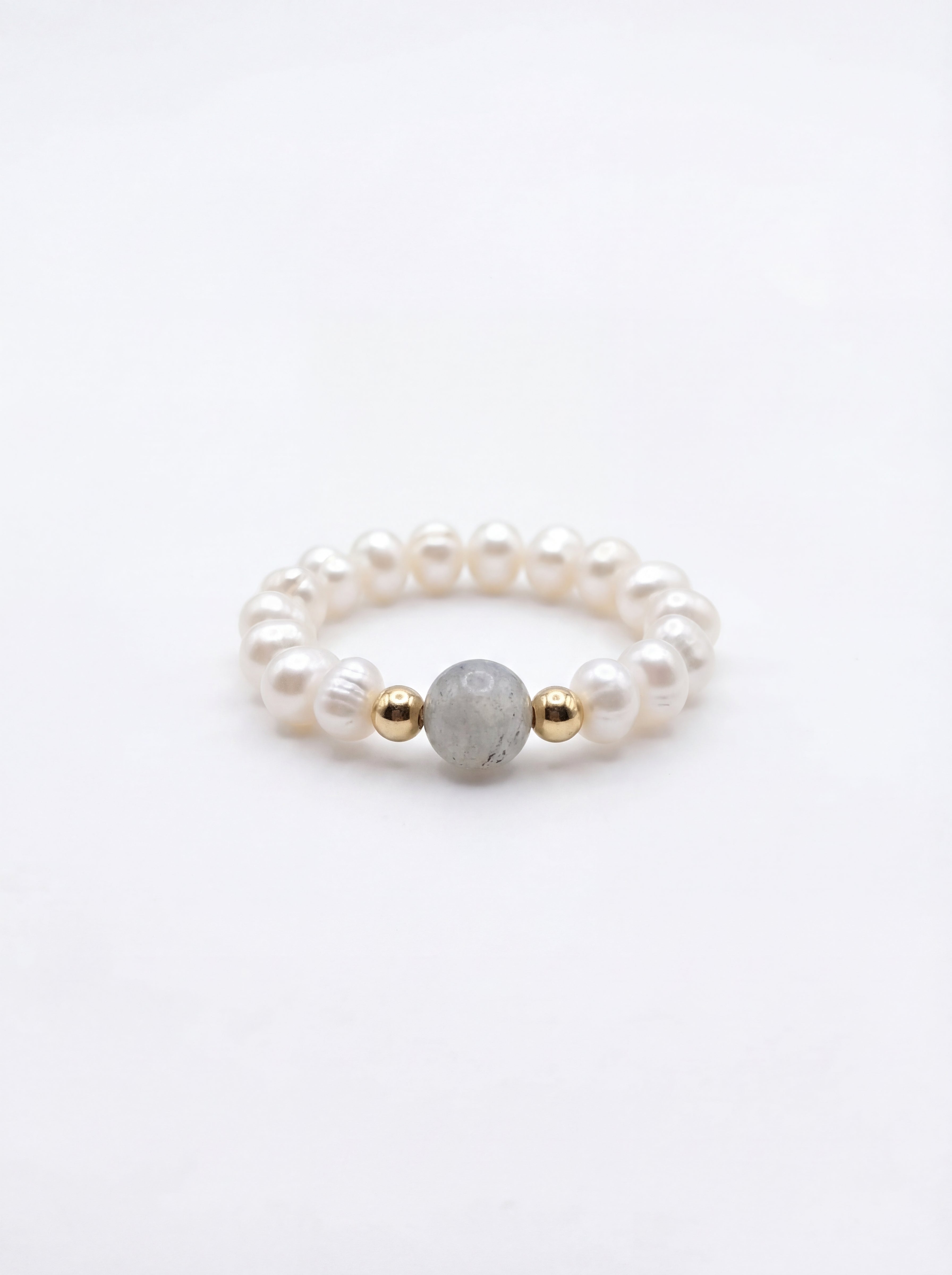 Pearl ring with gold and gray beads on a white background