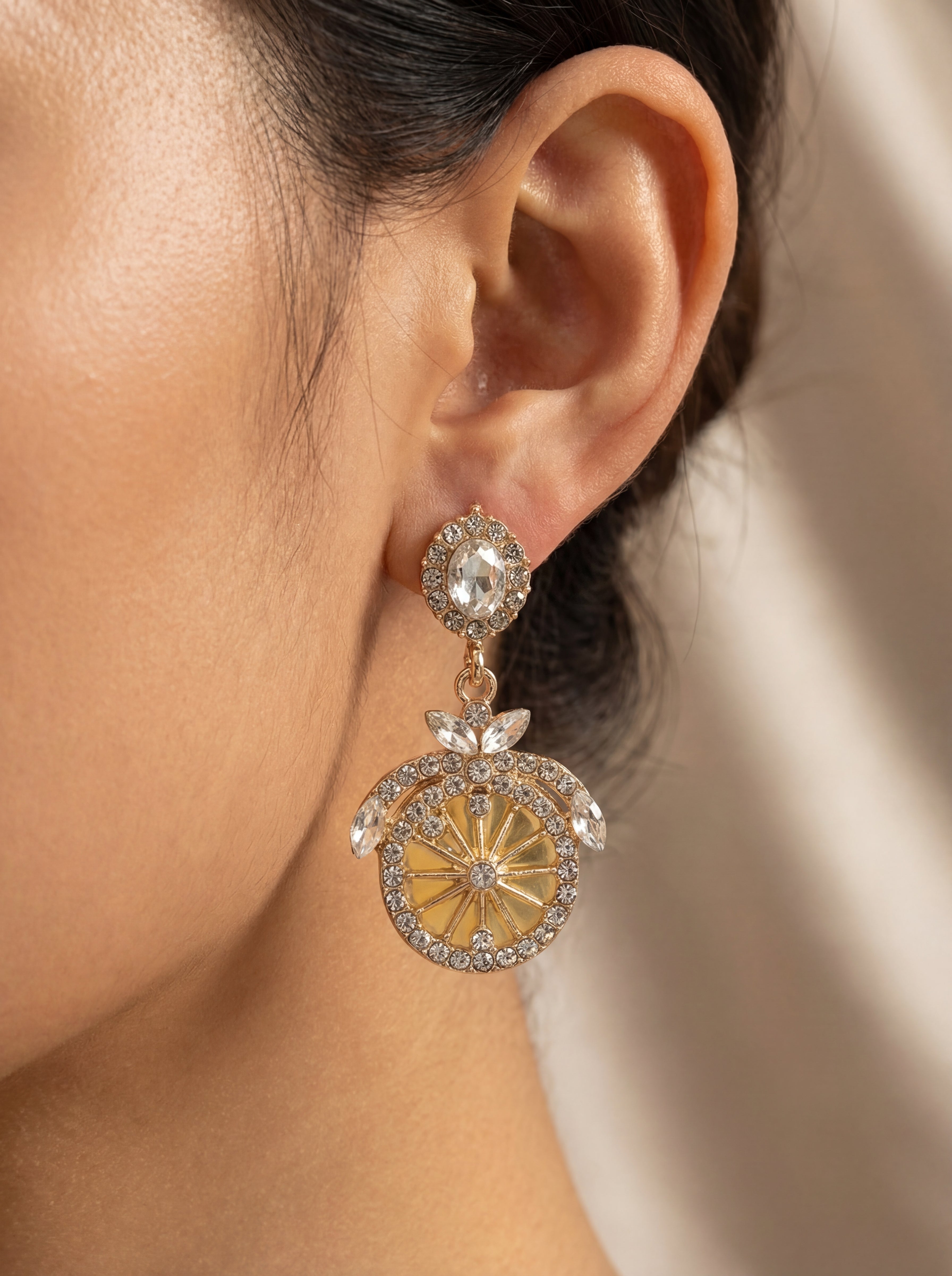 Close-up of a person wearing a sparkling earring with a neutral background