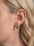 Gold earrings worn by a person with blonde hair.