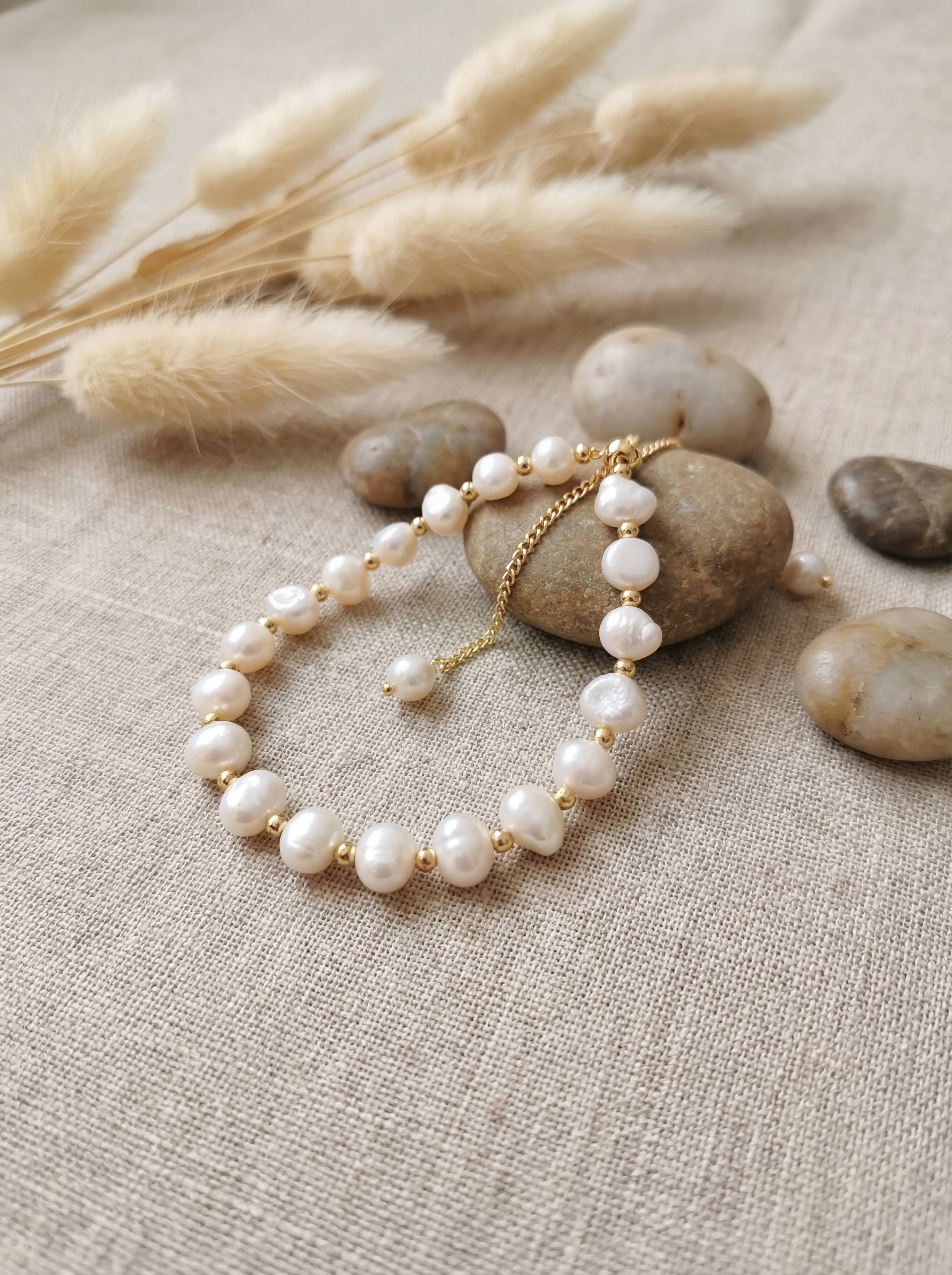 Pearl bracelet on a stone with dried grass and stones in the background