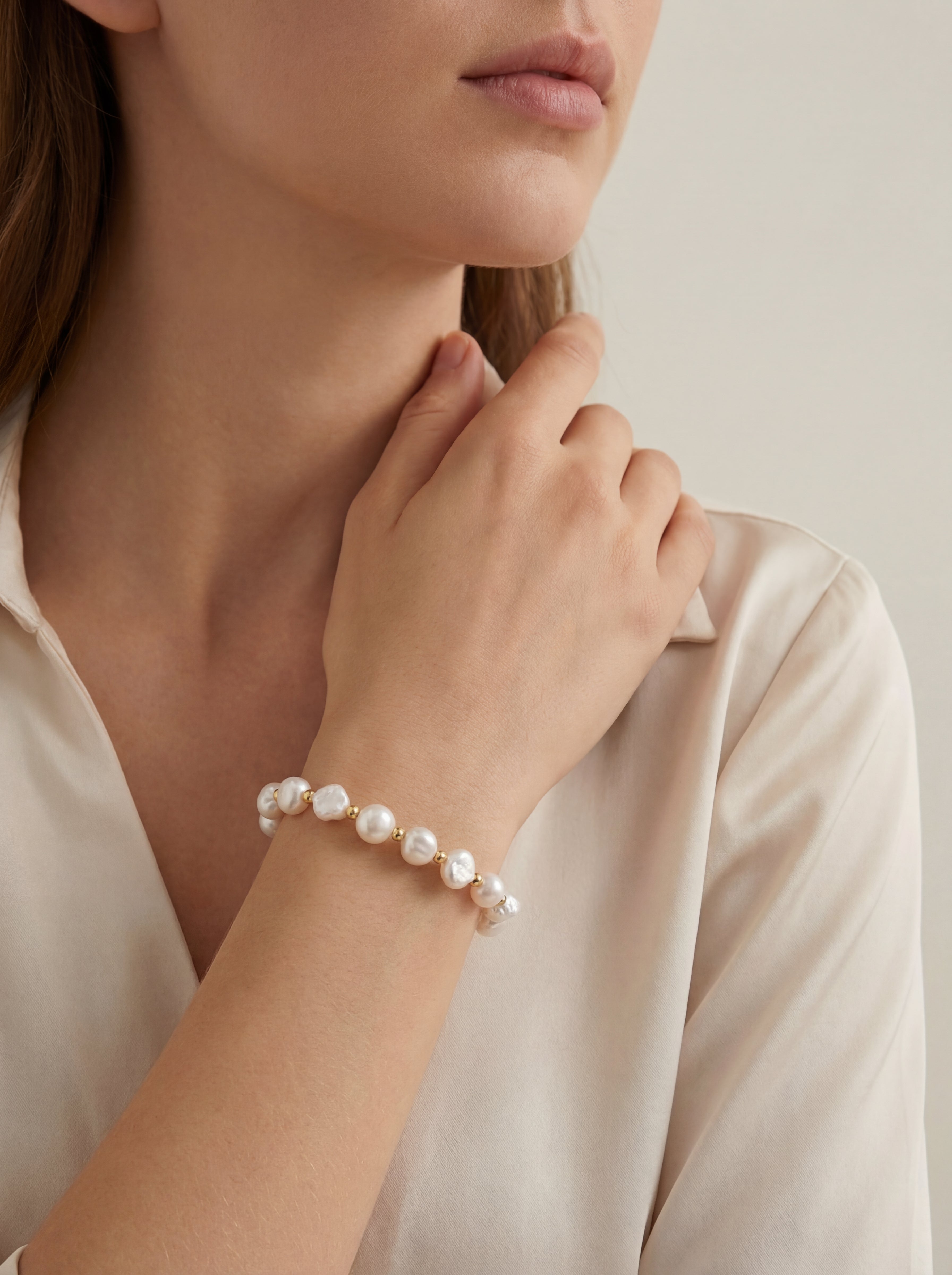 Pearl bracelet on a person's wrist with a neutral background