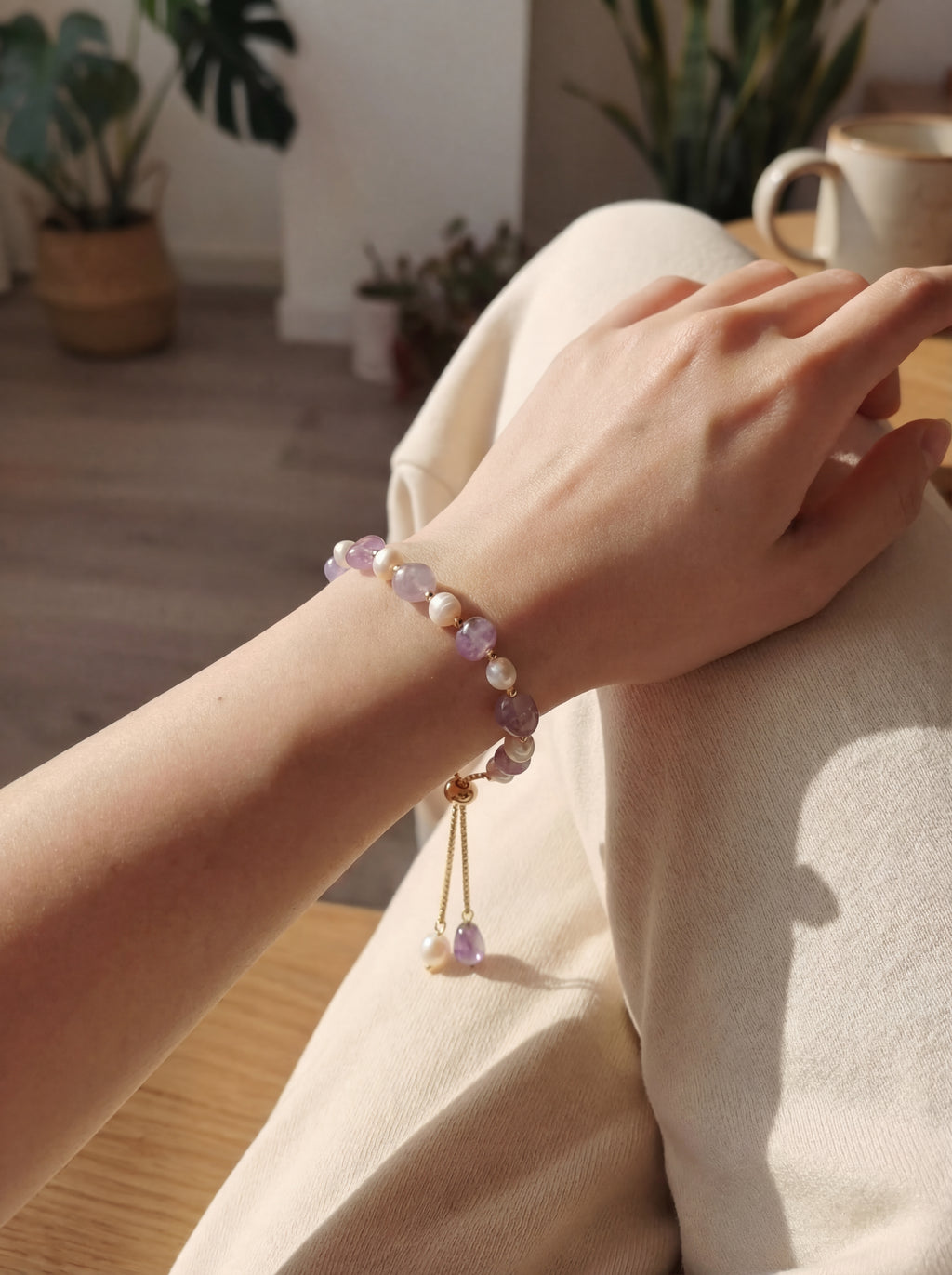 Hand wearing a beaded bracelet with a blurred indoor background