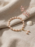 Pearl bracelet on a beige fabric background with dried flowers and a shell.