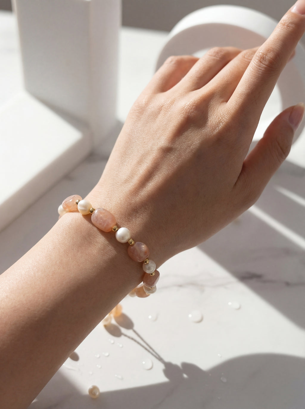 Hand wearing a bracelet with beads on a light surface