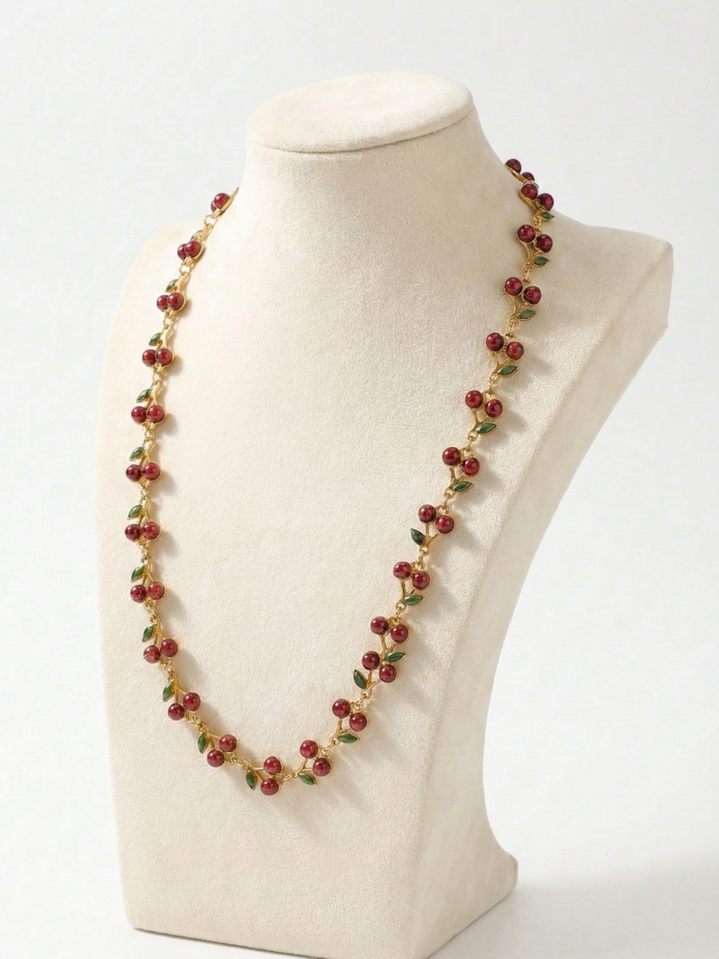 Necklace with red and green beads on a mannequin bust against a white background