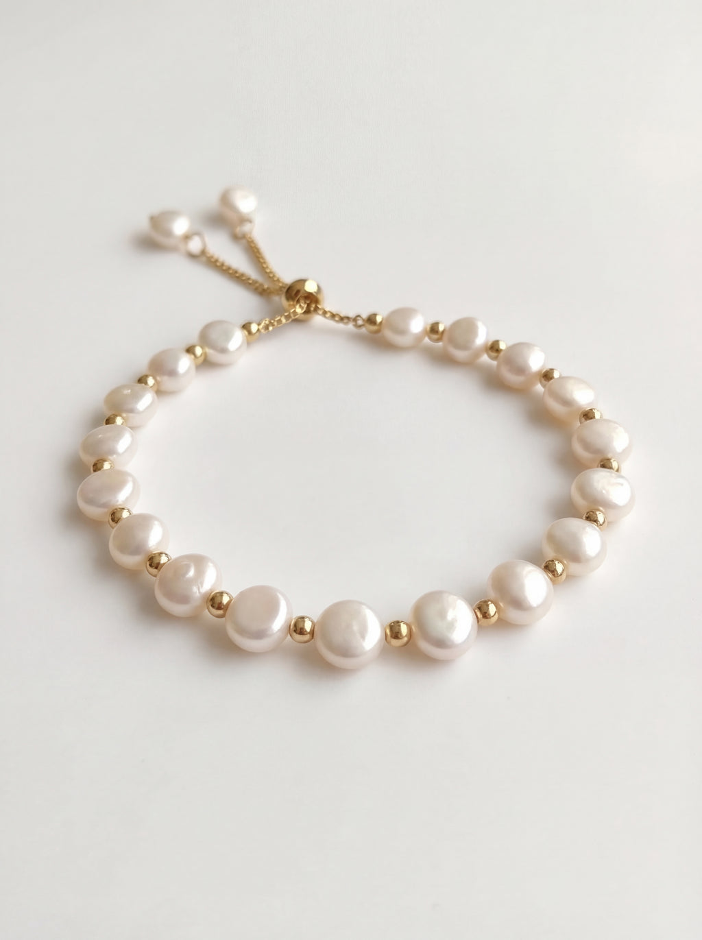 Pearl bracelet with gold accents on a light gray background