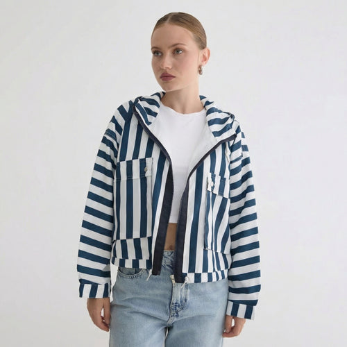 Una mujer que lleva una chaqueta cortavientos informal con capucha a rayas azules y blancas.