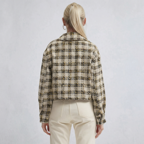 Una mujer lleva puesta una sobrecamisa oversize texturizada a cuadros en tono beige vista desde atrás.
