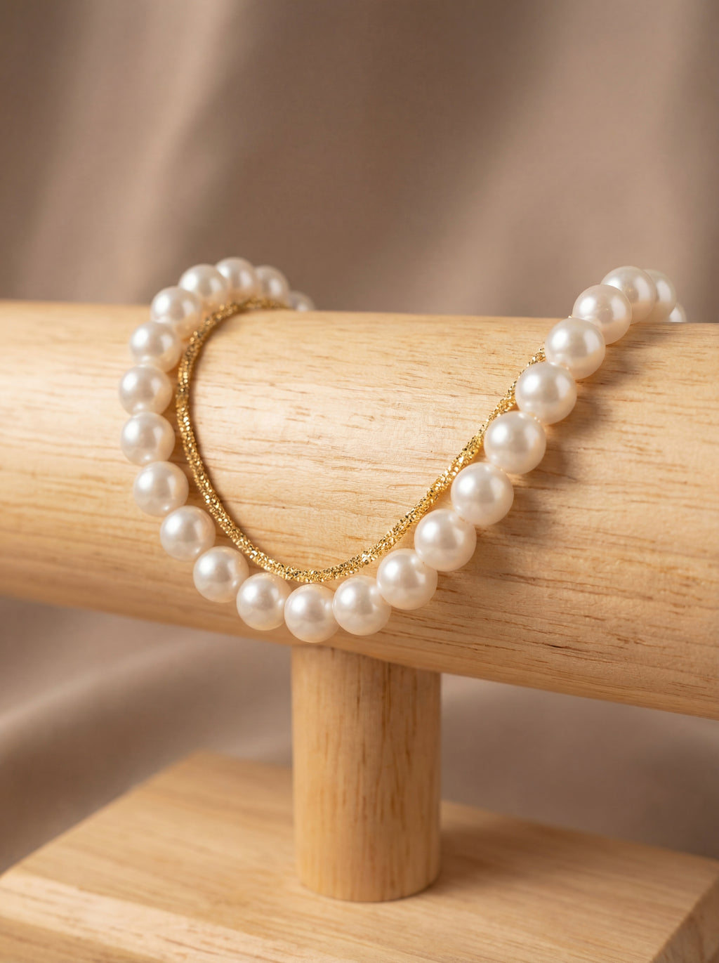 Pearl bracelet with gold heart on a wooden stand against a beige background