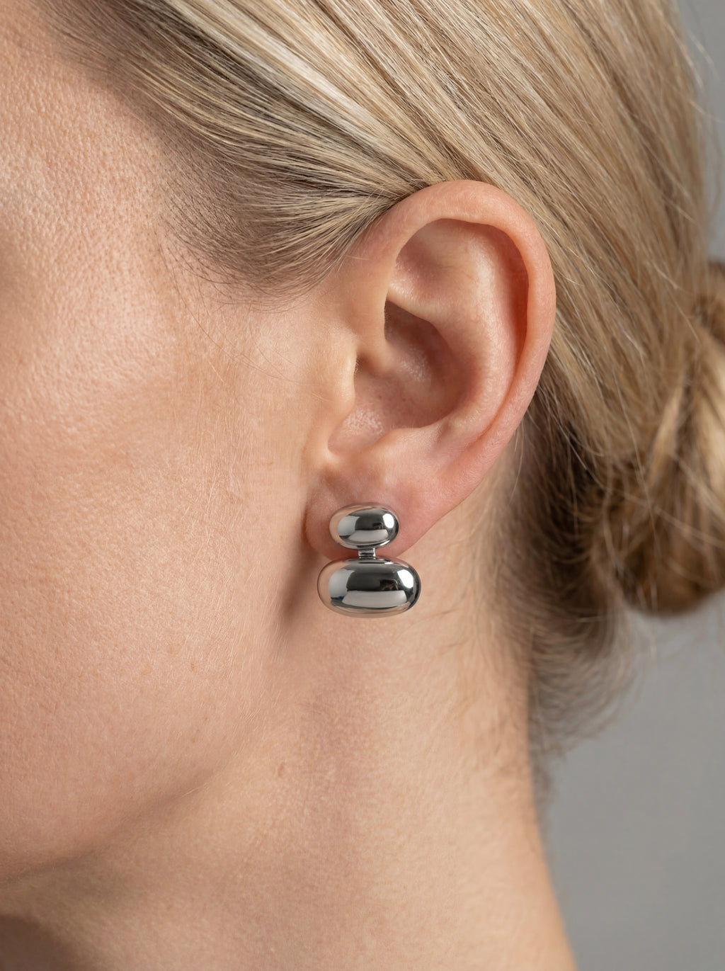 Person wearing pair of silver oval-shaped cufflinks 
