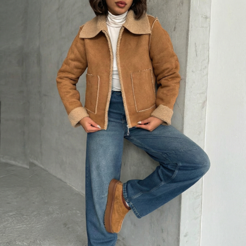 Kort aviator-jakke i lysebrunt rusindsskinslook med blød teddy-kant, båret med blå jeans.