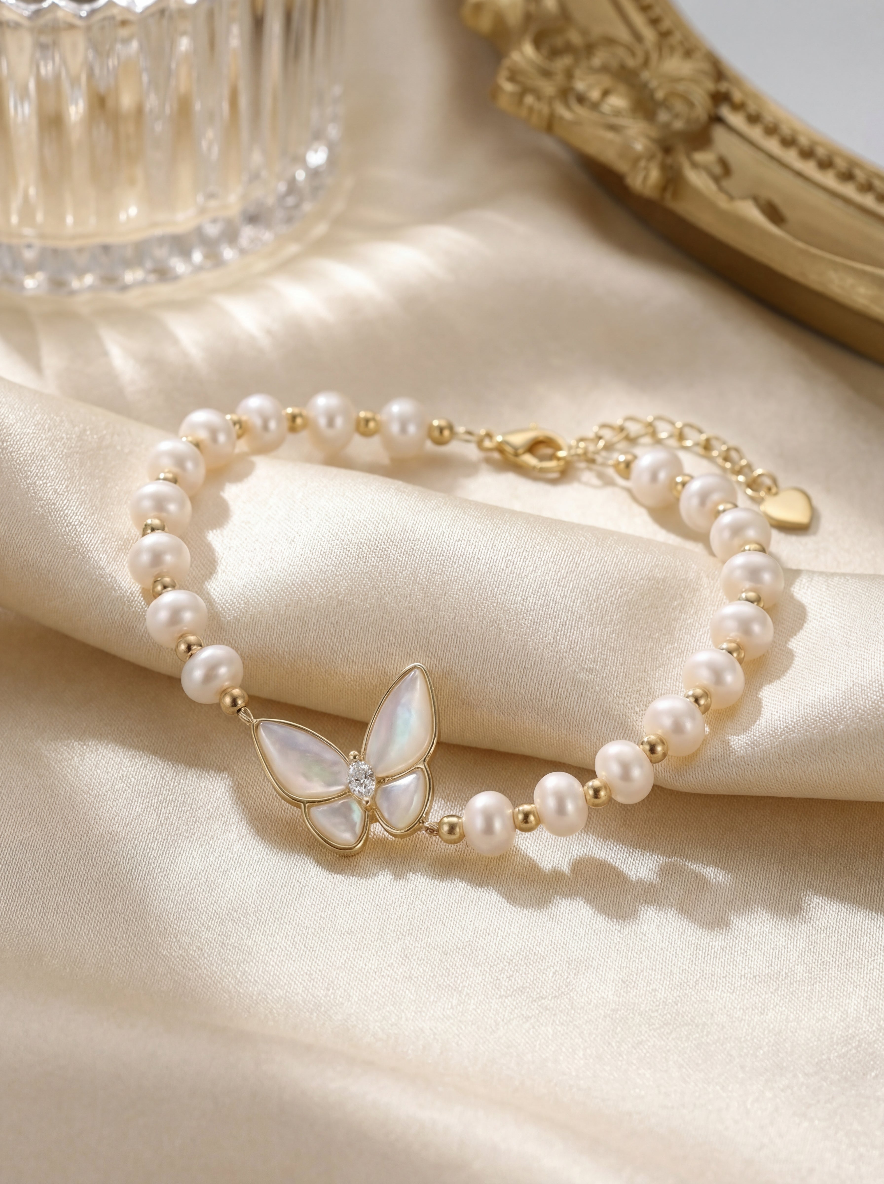 Pearl bracelet with a butterfly charm on a soft fabric background