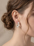 Close-up of a person wearing pearl earrings with a neutral background